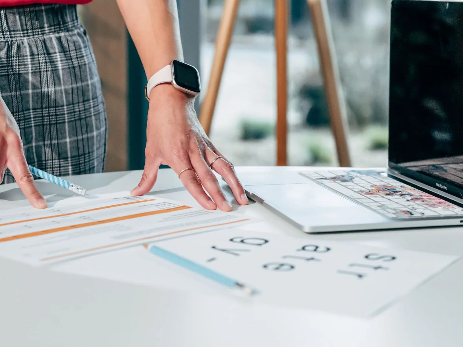Hands organising business reports beside a laptop